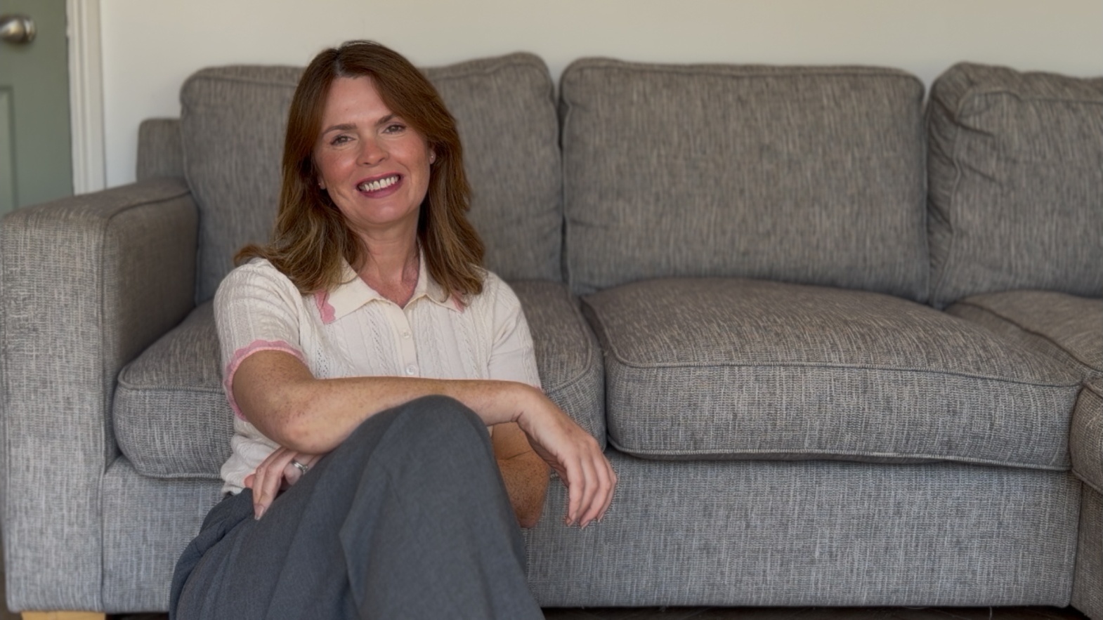 Mel sitting on a grey sofa